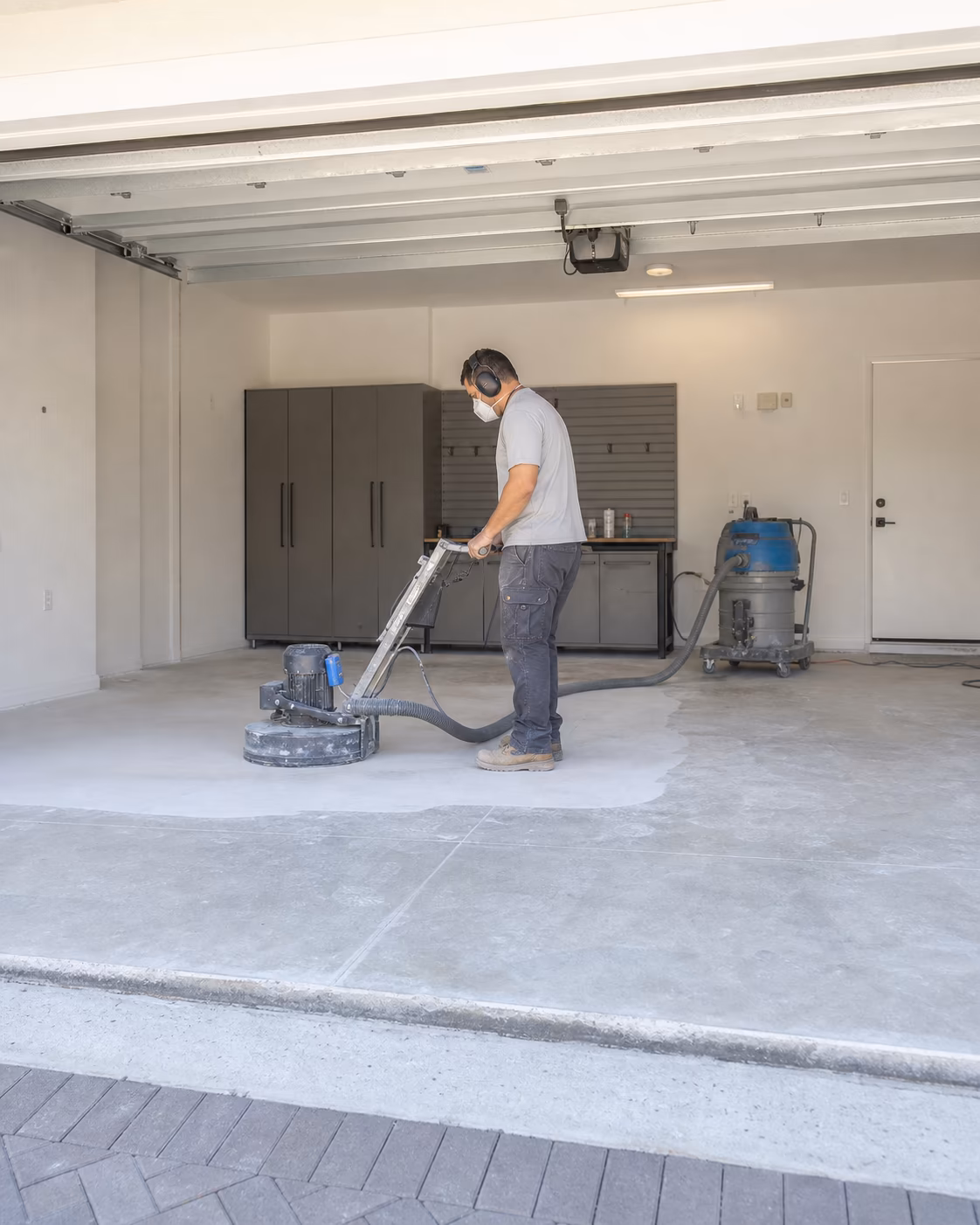 Installer grinding bare concrete in a two-car garage before coating